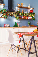 Christmas kitchen with a Christmas tree and festive lighting in the style of bokeh on the background of garlands decorated for the holiday. table in the kitchen. Christmas table setting with oranges.