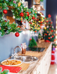 Christmas home room with Christmas tree and festive bokeh lighting, on background kitchen decorated for holiday . Christmas and new year interior-blurred background. Lots of lights that glow in dark.