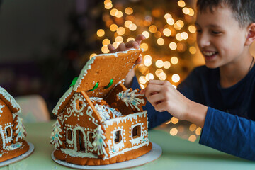 Handmade Christmas gingerbread house, child opens lid and takes gingerbread decorated with sweets...