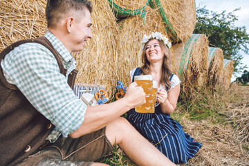 Young woman and man with beer glass and pretzel on wooden background .Oktoberfest concept