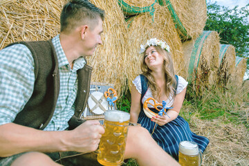Young woman and man with beer glass and pretzel on wooden background .Oktoberfest concept