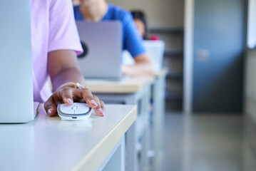 Close up of dark skin hand using computer mouse at classroom, unrecognizable girl and colleagues.