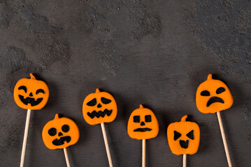 Themed October dessert. Vegan Pumpkin jelly candies on a wooden stick. Halloween. Dark background. Top view. Copy space