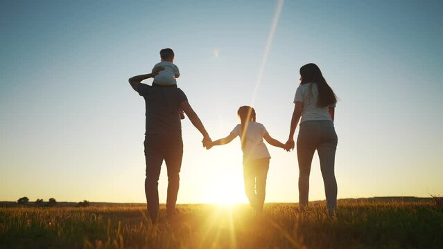 people in the park. happy family walking silhouette at sunset. mom dad and daughters walk holding hands in the park. happy family childhood dream concept. parents and children go back sun silhouette