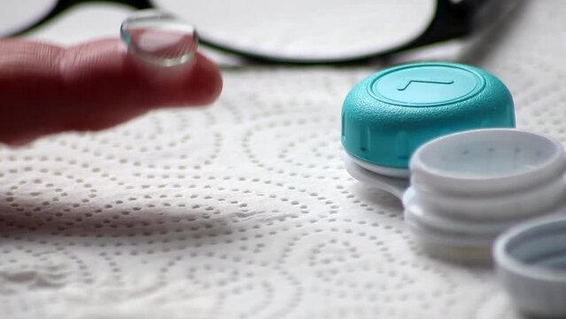 Male hands switching from eye glasses to contact lenses with hygienic care taking them out of the box to correct vision sight as nearsightedness or farsightedness by optometry eyewear for clear sight