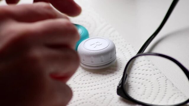 Male hands switching from eye glasses to contact lenses with hygienic care taking them out of the box to correct vision sight as nearsightedness or farsightedness by optometry eyewear for clear sight