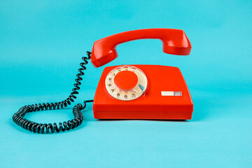 Old phone on a blue background. Antique phone with a tube. Red telephone with a receiver. Retro telephone