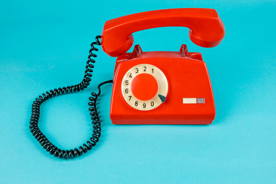 Old phone on a blue background. Antique phone with a tube. Red telephone with a receiver. Retro telephone