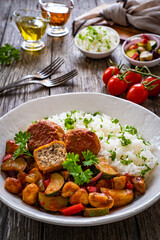 Delicious stew - white rice with vegetables and meatballs on wooden table
