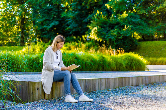 Coffee break - beautiful woman reading book in city park