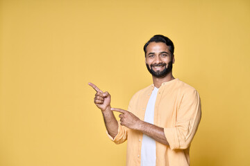 Happy indian man looking at camera pointing aside with fingers hand gesture indicating advertising...