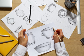 The designer draws sketches of dishes on paper. The artist creates kitchen utensils for production.