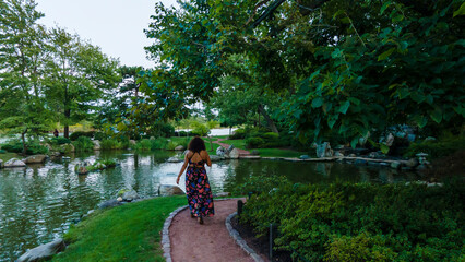 black woman walking around happy and cheerful in an outdoor Chicago park during the day. she is smiling while enjoying all of nature in a beautiful summer dress.