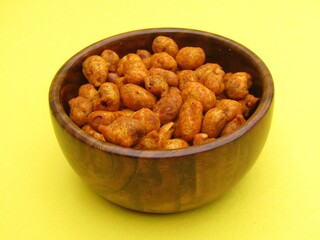 Masala peanuts in a wooden bowl on yellow background 