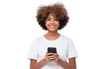 African american smiling teenage girl with afro hairstyle holding phone with both hands, chatting...