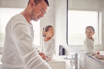 Fototapeta premium Bathroom, man and child smile in morning before work and school. Cleaning, ready for the day and a father and daughter in a sunny bath room of family home. Happy kid looking at reflection in mirror.
