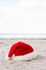 Christmas background Santa Claus hat on the beach 