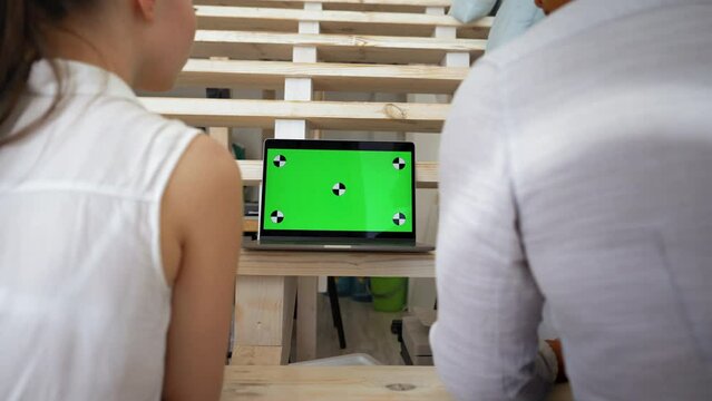 Man and woman watch movie on laptop standing at wooden stairs step in living room. Modern device with chromakey screen closeup replace with Your content