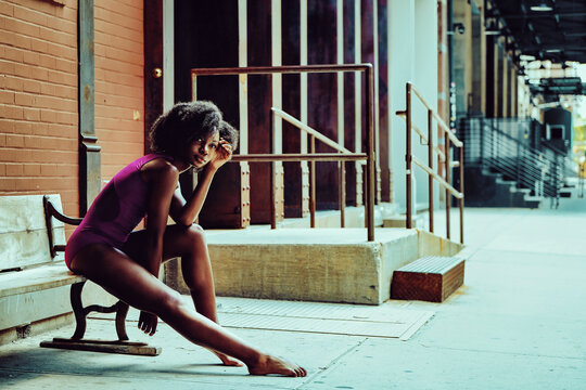 ballerina modern dancer outdoors sitting on a bench