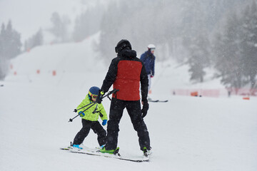 Ski instructor teaches the child to ski on the slope