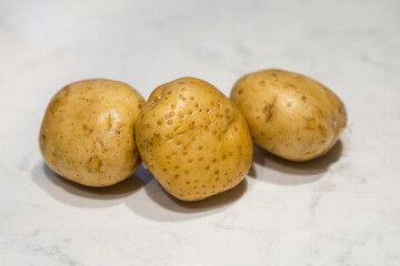 Group of 3 small unpeeled, raw potatoes.