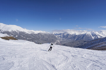 Fototapeta na wymiar Woman skier on the ski slope in the mountains