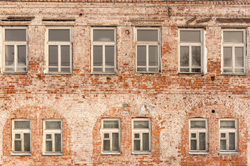 the wall of an old red brick two-story building with partially frozen wooden windows.