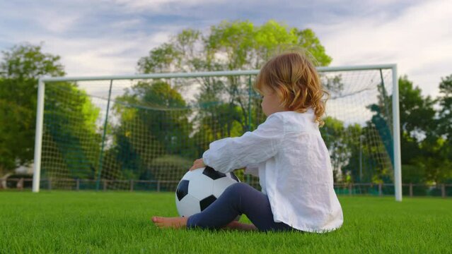 Baby girl play ball in the park. Happy family kid dream concept. Kid baby play football soccer in nature park. Fun baby kicking the ball. Happy family childhood