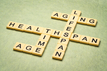 aging, time, lifespan and healthspan crossword in ivory letter tiles against textured handmade paper, age and longevity concept