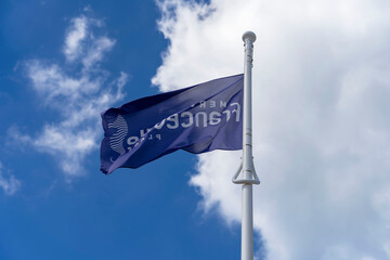 The blue flag of the city of Merville-Franceville-Plage close-up against a bright blue sky. Normandy, France.