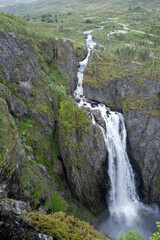 Wonderful landscapes in Norway. Vestland. Beautiful scenery of Voringfossen waterfall in the Mabodalen valley on the Hardanger scenic route. Mountains, trees in background. Cloudy day. Selective focus