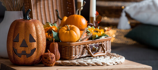 A wicker basket with pumpkins, Jack's Pumpkin and candles in the interior of the living room on a...