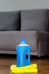 Floor cleaner in a plastic bottle and a floor cloth on the parquet floor indoors. House cleaning