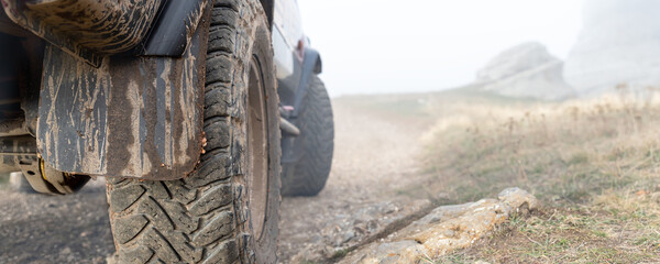 Close-up detail bottom POV view of 4x4 awd suv vehicle on dirt gravel unpaved road in autumn at...