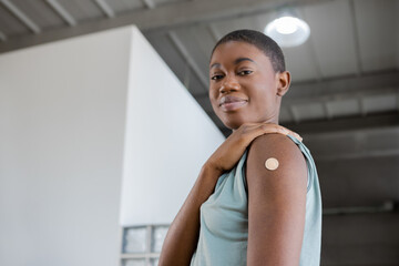 African American woman looking at camera showing adhesive bandage plaster on arm