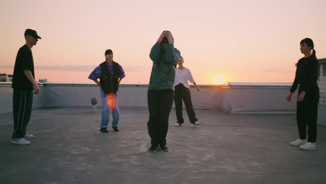 cool boy is dancing breakdance in street dance battle on roof, youth hang out together and have fun