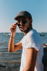 Fototapeta na wymiar Hombre joven modelo con camisa blanca, gafas de sol y gorra