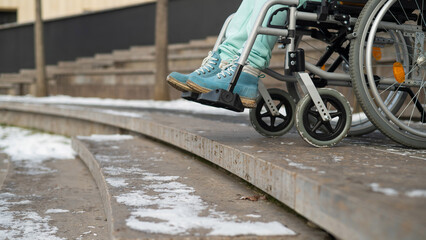 Woman in a wheelchair near the stairs in the park in winter.