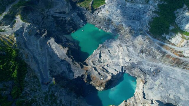 4K : Drones are flying over a large quarry, many machines are working. Turquoise puddles in the quarry. stone industry. stone is a important construction material used to build infrastructure
