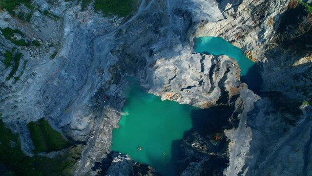 4K : Drones are flying over a large quarry, many machines are working. Turquoise puddles in the quarry. stone industry. stone is a important construction material used to build infrastructure
