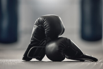 Boxing gloves on the floor of a gym after exercise, training and workout. Pair of sport handwear or equipment on the ground after fighting match, practice or punching in a competitive sports club - obrazy, fototapety, plakaty