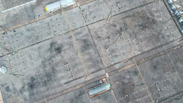 4K : Aerial top view from a drone flying over a high voltage power tower in substation. Electric power industry.
