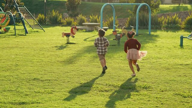 Niños amigos hermanos primos felices Corriendo en parque con pasto verde jugando a competencia entre plantas y pasto divertidos y disfrutando de un hermoso atardecer latinos rubios