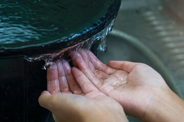 Hands hold water that overflows from a bucket, like a waterfall. soft and selective focus.
