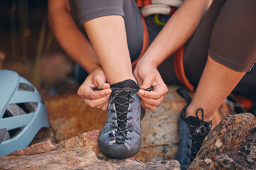 Woman tying her hiking shoes in nature preparing for a rock climbing or trekking exercise. Fitness,...