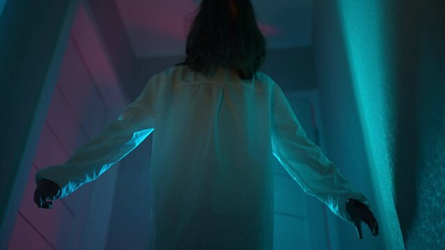 girl in a ghostly white halloween sundress, scaring someone in the hallway of a haunted house. 4k footage