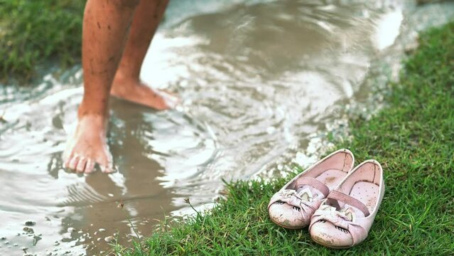 piernas de ni&ntilde;a festejando celebrando en parque brincando en charco con agua de lluvia y lodo con tierra sucia disfrutando y divertida en el parque al exterior al aire libre en un hermoso d&iacute;a