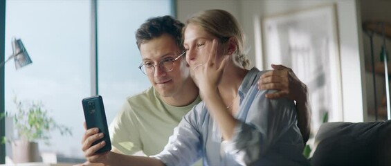 WIDE Young couple announcing their engagement to friends or family during video call, bride-to-be showing her ring finger to a phone camera. Shot with 2x anamorphic lens - Powered by Adobe