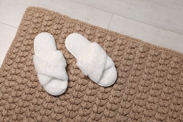 Soft white slippers on carpet in room. Space for text
