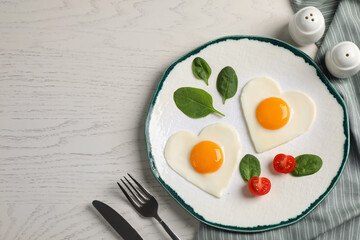 Heart shaped fried eggs served on white wooden table, flat lay. Space for text
